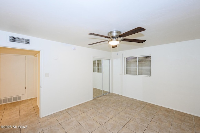 empty room featuring light tile patterned floors, a ceiling fan, and visible vents