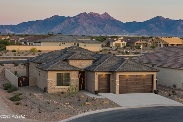 view of front of home with driveway, stucco siding, an attached garage, and a mountain view