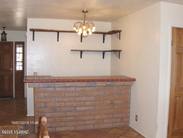 interior space featuring tile counters, tile patterned floors, open shelves, and an inviting chandelier