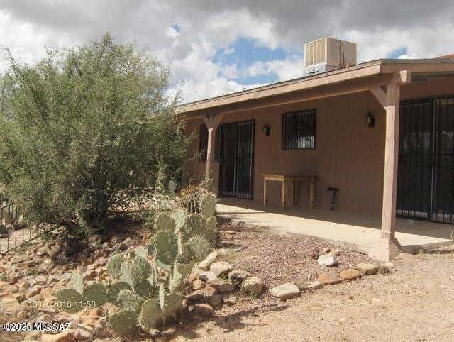 rear view of house featuring central AC unit, a patio, and stucco siding