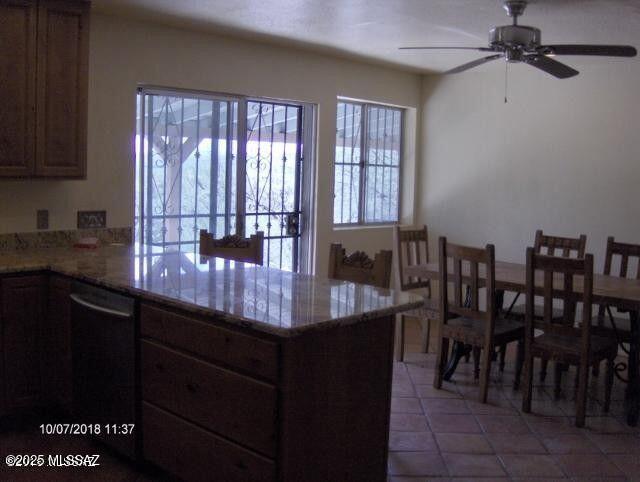 kitchen with a peninsula, black dishwasher, ceiling fan, and plenty of natural light