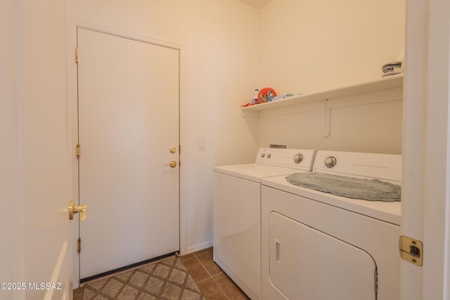 clothes washing area featuring separate washer and dryer, laundry area, light tile patterned floors, and baseboards
