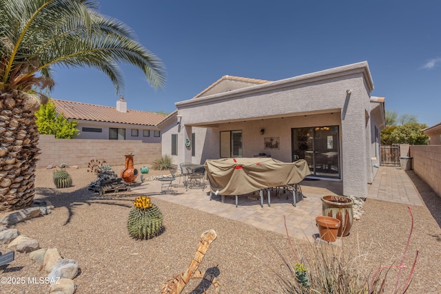 back of property featuring stucco siding, a tiled roof, a fenced backyard, and a patio