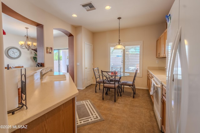 kitchen featuring a sink, white appliances, arched walkways, and plenty of natural light