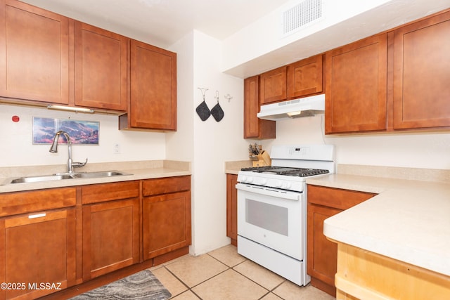 3541 E Cody St, Tucson, AZ 85716 - kitchen featuring under cabinet range hood, white gas stove, a sink, light countertops, and light tile patterned floors