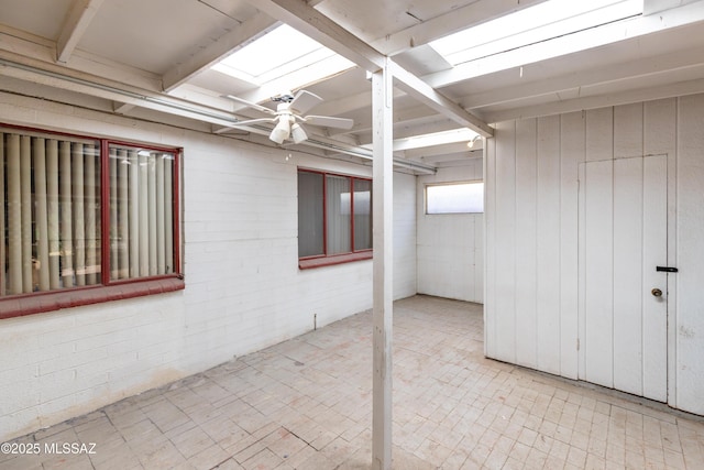 basement with a ceiling fan and brick wall