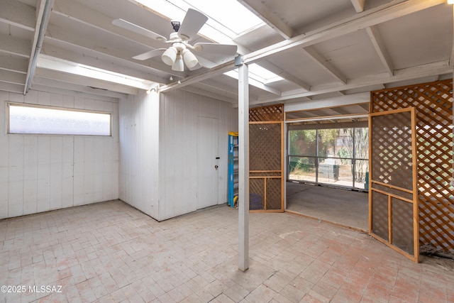 interior space featuring wooden walls, brick floor, and a ceiling fan