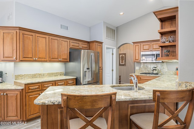 38459 S Bellrock Ct, Tucson, AZ 85739 - kitchen featuring appliances with stainless steel finishes, a sink, open shelves, a peninsula, and a kitchen bar