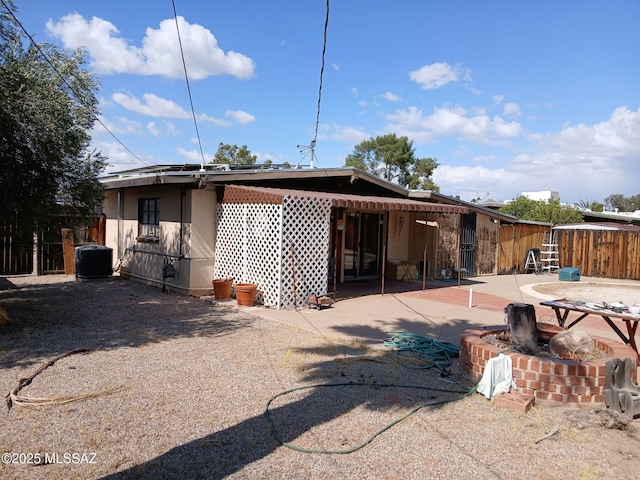 rear view of property with fence, a patio area, and central AC