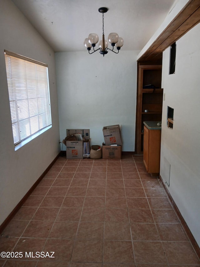 dining area featuring baseboards, dark tile patterned flooring, and an inviting chandelier
