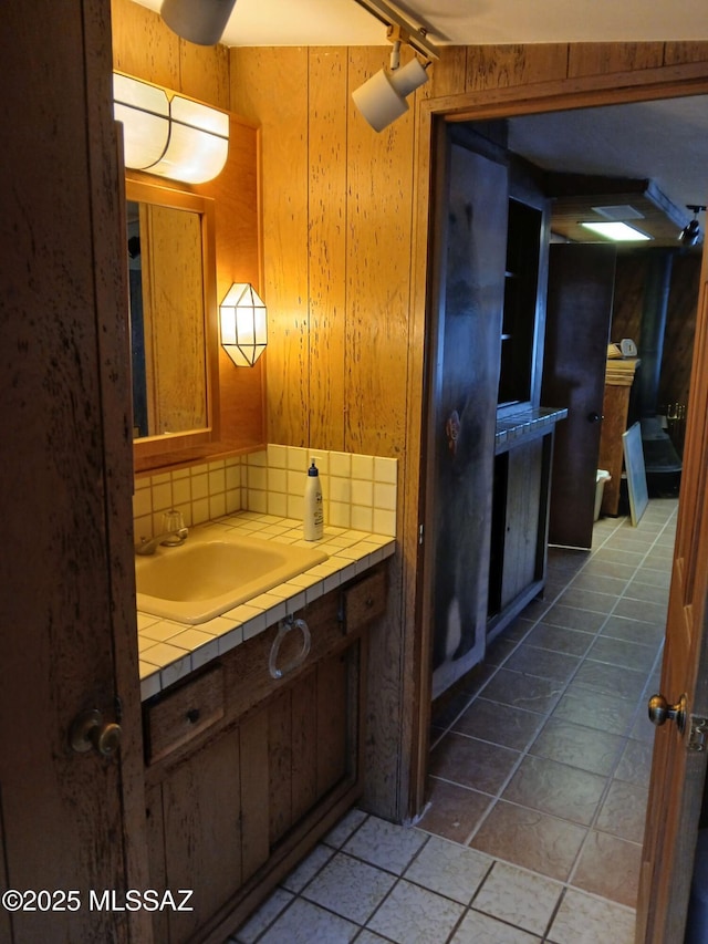 bathroom with tile patterned floors, wooden walls, tasteful backsplash, and vanity