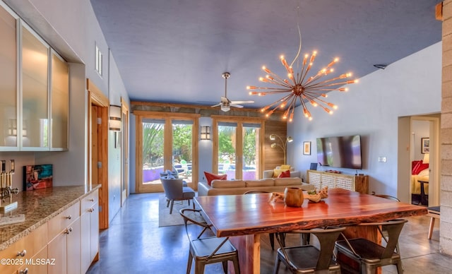 dining space with concrete floors and ceiling fan with notable chandelier