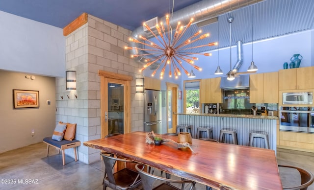 dining area with a chandelier, concrete flooring, visible vents, and a high ceiling