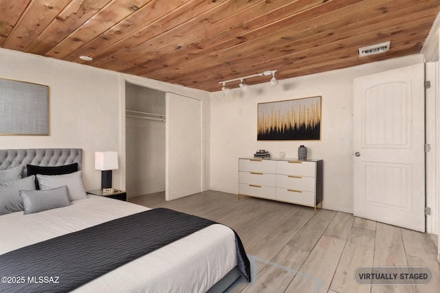 bedroom featuring a closet, rail lighting, visible vents, wooden ceiling, and light wood-style flooring