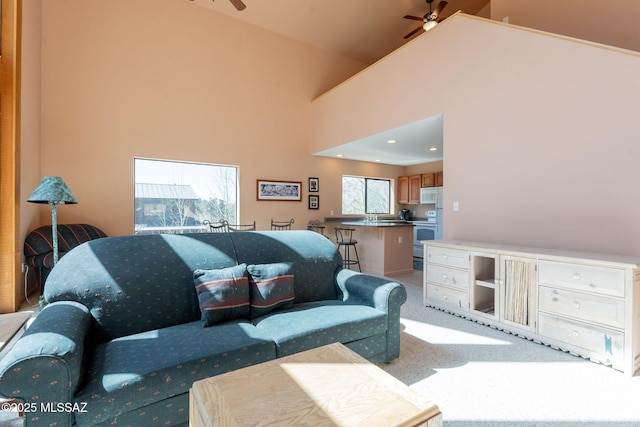 living area featuring a ceiling fan, high vaulted ceiling, and carpet floors