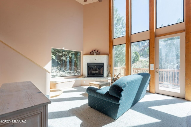 living room featuring carpet, a tiled fireplace, and a towering ceiling