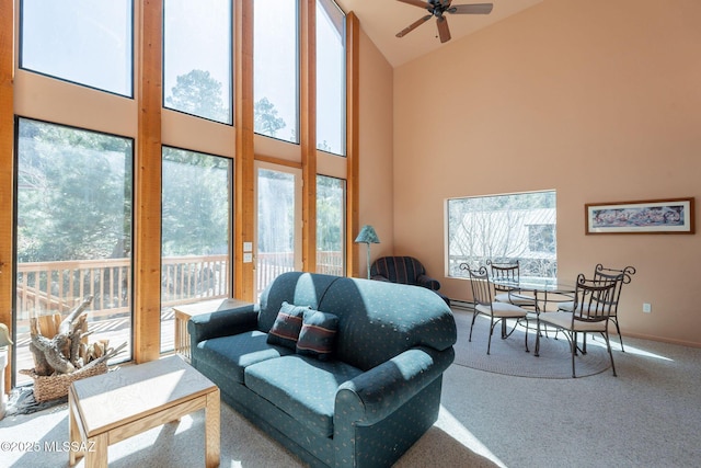 carpeted living room featuring baseboards, ceiling fan, and high vaulted ceiling