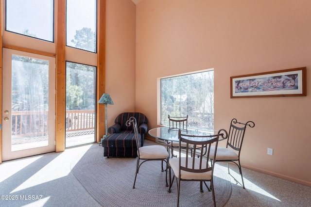 dining space featuring baseboards, carpet flooring, and a high ceiling