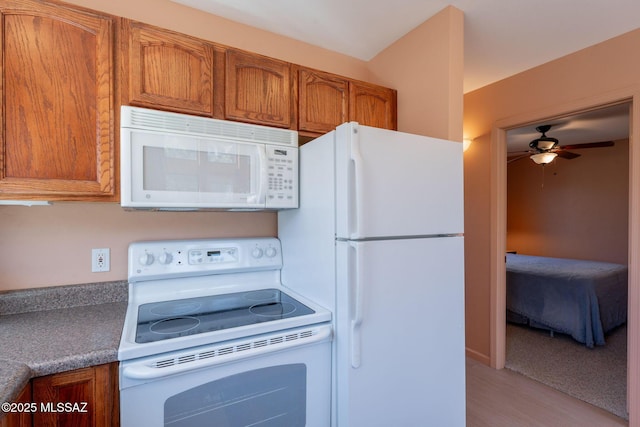kitchen featuring light wood finished floors, brown cabinetry, a ceiling fan, and white appliances