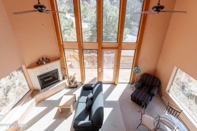 living room with a towering ceiling, carpet, a ceiling fan, and a healthy amount of sunlight