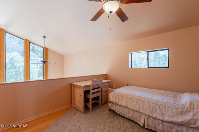 bedroom featuring a ceiling fan, baseboards, wood finished floors, and lofted ceiling