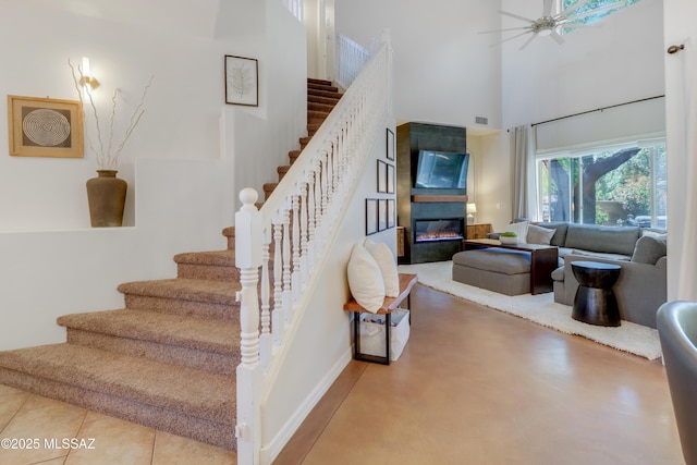 29 W Camino Rancho Viejo, Sahuarita, AZ 85629 - staircase featuring a high ceiling, a glass covered fireplace, ceiling fan, and baseboards