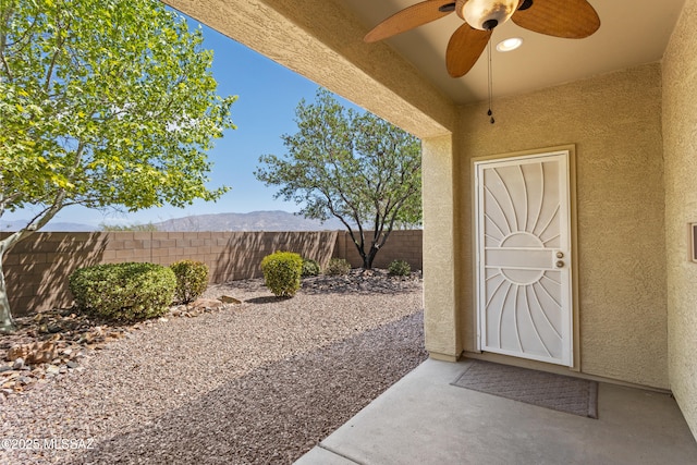 11413 E Squash Blossom Loop, Tucson, AZ 85747 - doorway to property featuring a ceiling fan, stucco siding, fence, and a patio