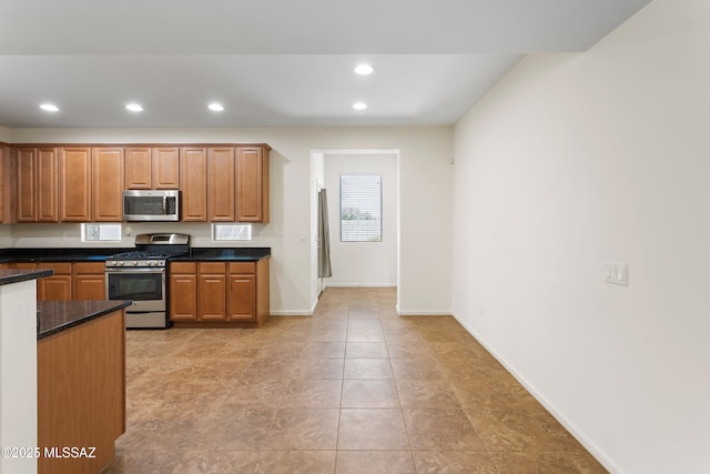 11413 E Squash Blossom Loop, Tucson, AZ 85747 - kitchen with stainless steel appliances, recessed lighting, baseboards, brown cabinetry, and dark stone counters