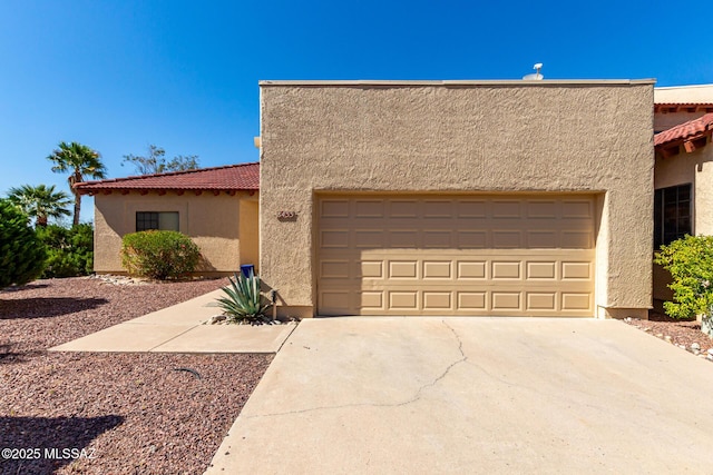 view of front of home with a garage, stucco siding, a tiled roof, and driveway