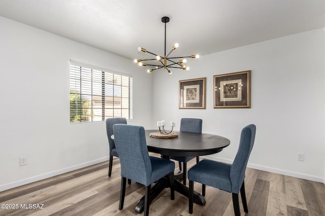 dining area featuring a chandelier, light wood-style flooring, and baseboards