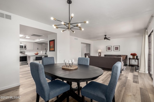 dining area with light wood finished floors, visible vents, and ceiling fan with notable chandelier