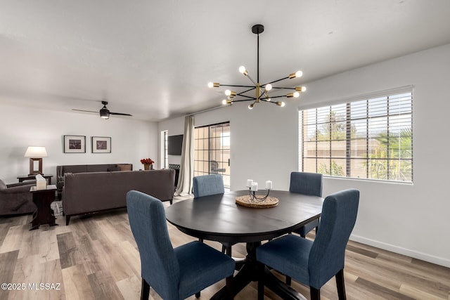 dining room featuring baseboards, light wood-style floors, and ceiling fan with notable chandelier