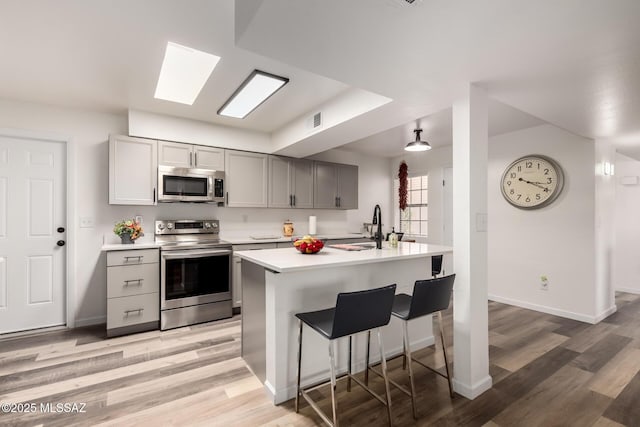 kitchen featuring visible vents, light wood-style floors, light countertops, appliances with stainless steel finishes, and gray cabinets