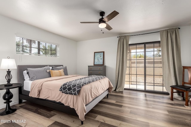 bedroom with wood finished floors, access to outside, and multiple windows