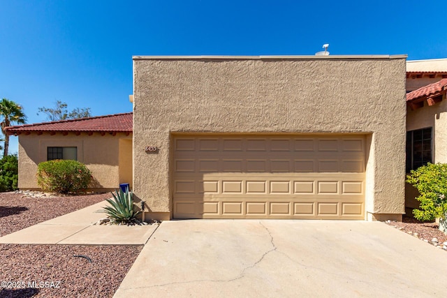 view of front of house with a tile roof, stucco siding, and driveway