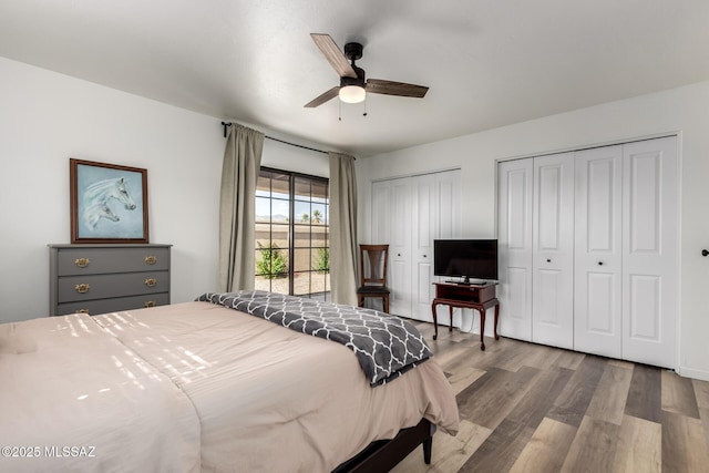 bedroom with ceiling fan, wood finished floors, and multiple closets