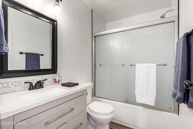full bath featuring toilet, vanity, and shower / bath combination with glass door