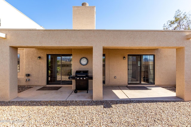 rear view of property with stucco siding and a patio