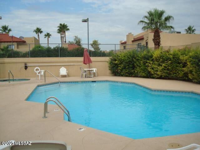 community pool with a patio and fence