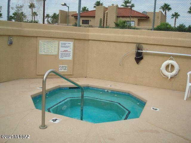 view of pool featuring a hot tub and fence
