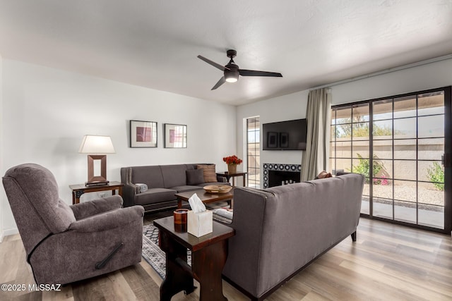 living room with wood finished floors, a ceiling fan, and a fireplace