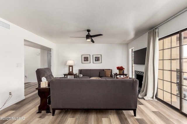 living room with visible vents, wood finished floors, a ceiling fan, and a fireplace