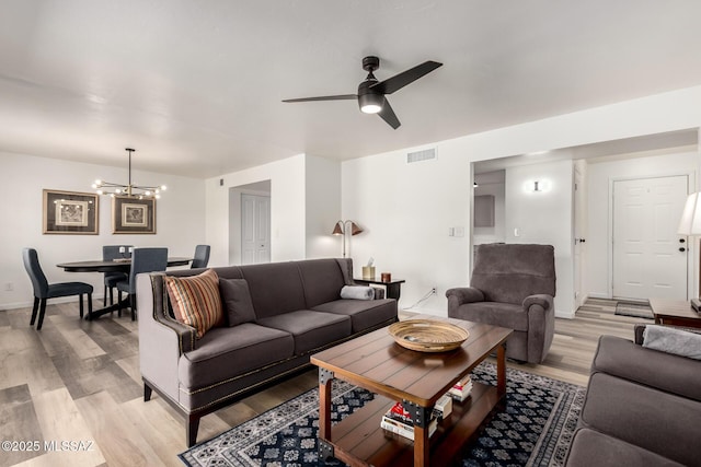 living area with light wood finished floors, ceiling fan with notable chandelier, baseboards, and visible vents