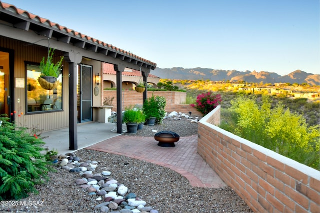 view of patio / terrace with an outdoor fire pit, fence, and a mountain view