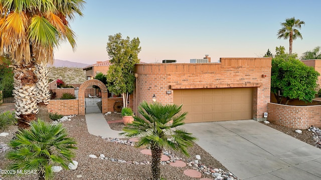 view of front of house with an attached garage, stucco siding, driveway, and a gate