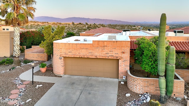 view of front facade with brick siding, a mountain view, and driveway