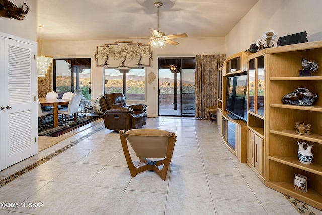 living area with light tile patterned floors and ceiling fan with notable chandelier