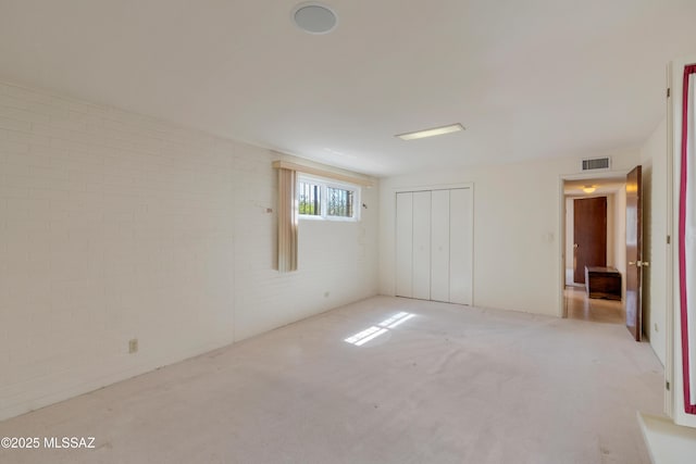 1047 E Hedrick Dr, Tucson, AZ 85719 - unfurnished bedroom with light colored carpet, brick wall, and a closet
