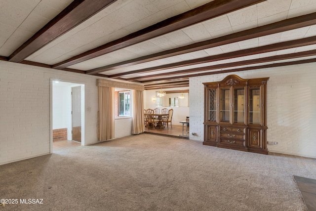 1047 E Hedrick Dr, Tucson, AZ 85719 - unfurnished living room with brick wall, beamed ceiling, and carpet flooring