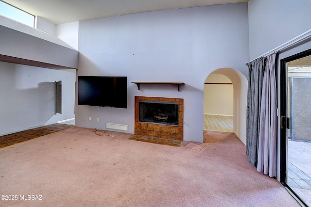 810 E Placita Leslie, Tucson, AZ 85718 - unfurnished living room with carpet floors, arched walkways, visible vents, and a tile fireplace